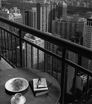 side table with coffee, food, books and glasses on South Park Tower balcony with NYC views