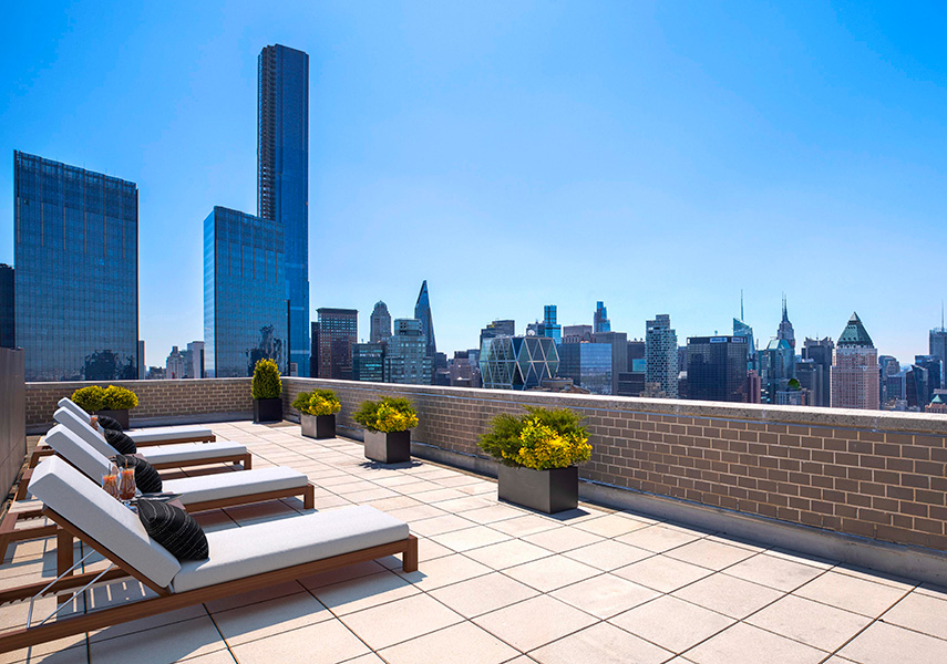 South Park Tower rooftop with lounge chairs and plant furnishings and view of the city
